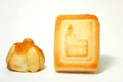 Das Bild zeigt zwei Backwaren. Links ist ein kleines rundes Gebäck mit Mandeln belegt, rechts ist ein rechteckiges Gebäck mit einem geprägten Muster auf der Oberseite. Der Hintergrund ist schlicht weiß.