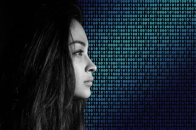 Das Profil einer Frau mit langen, dunklen Haaren, die nach links blickt. Der Hintergrund besteht aus einem Binärcodemuster in verschiedenen Blau- und Schwarztönen, was ein digitales und futuristisches Gefühl vermittelt. Die Beleuchtung hebt ihr Gesicht hervor und betont ihren nachdenklichen Ausdruck, als ob sie darüber nachdenkt, wie sie am besten einen Servicepartner für einen optimalen Webshop beauftragen kann.